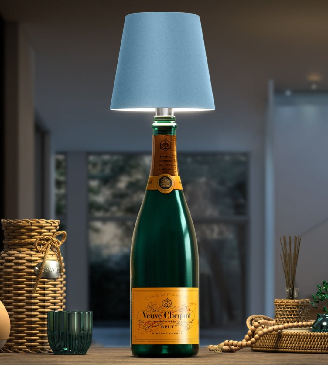 Lichtblauwe lampenkap op een groene champagnefles, omringd door rieten manden en kralen op een houten tafel. 6