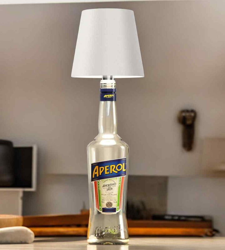 Witte lampenkap op een heldere fles met kleurrijk etiket, op een keukenblad in een lichte ruimte. 3