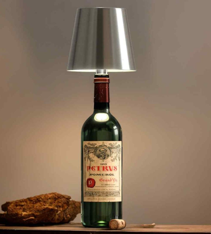 Zilverkleurige lampenkap op een groene wijnfles met oud etiket, naast een kurk en een stuk hout. 7
