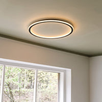 Brandende ronde plafondlamp met zwarte rand aan een plafond naast een wit raam met uitzicht op bomen. 8