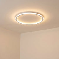 Aangezette witte ringlamp, schuin van onderaf gezien, die zacht licht over het crèmekleurige plafond en de muren verspreidt. 6
