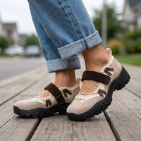 Beige schoenen met bruine klittenbandband en zwarte zool, gedragen met opgerolde jeans op een houten vlonder in een woonwijk. 6