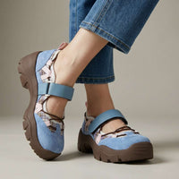 Blauwe suÃ¨de schoenen met ruitjesstof, roze accenten en bruine zool, gedragen met lichte jeans voor een neutrale studioachtergrond. 3