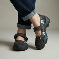 Donkergrijze schoenen met klittenbandband en lichtblauwe accenten, gedragen met opgerolde jeans in de studio, schuin van opzij gezien. 2