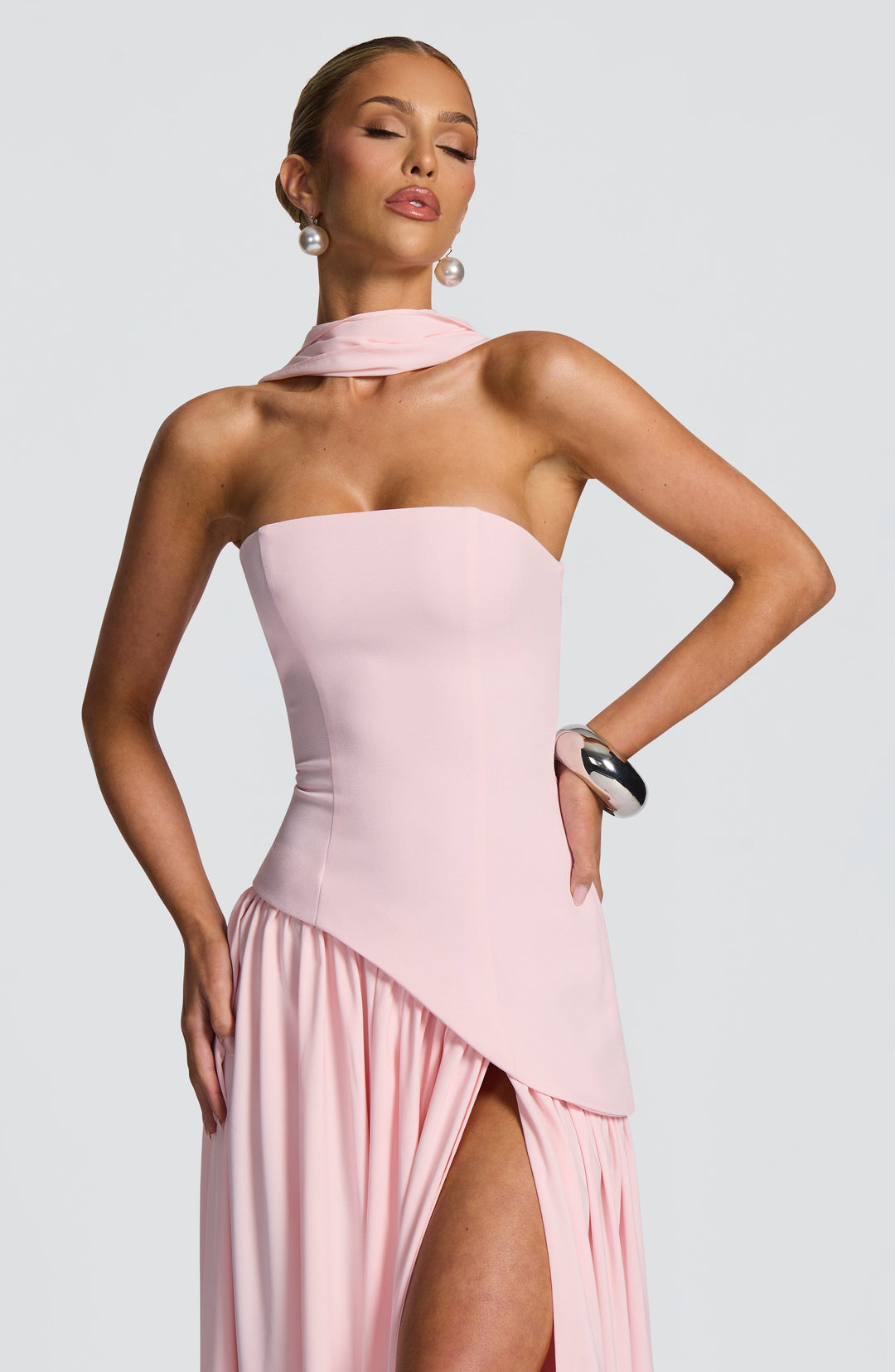 Close-up van het roze strapless lijfje met sjaalkraag, hand op de heup en hoge split 24