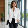 Vrouw loopt in een kantoorgang in een witte blazer met kabelstructuur en drie knopen, met zwarte pantalon en map. 1