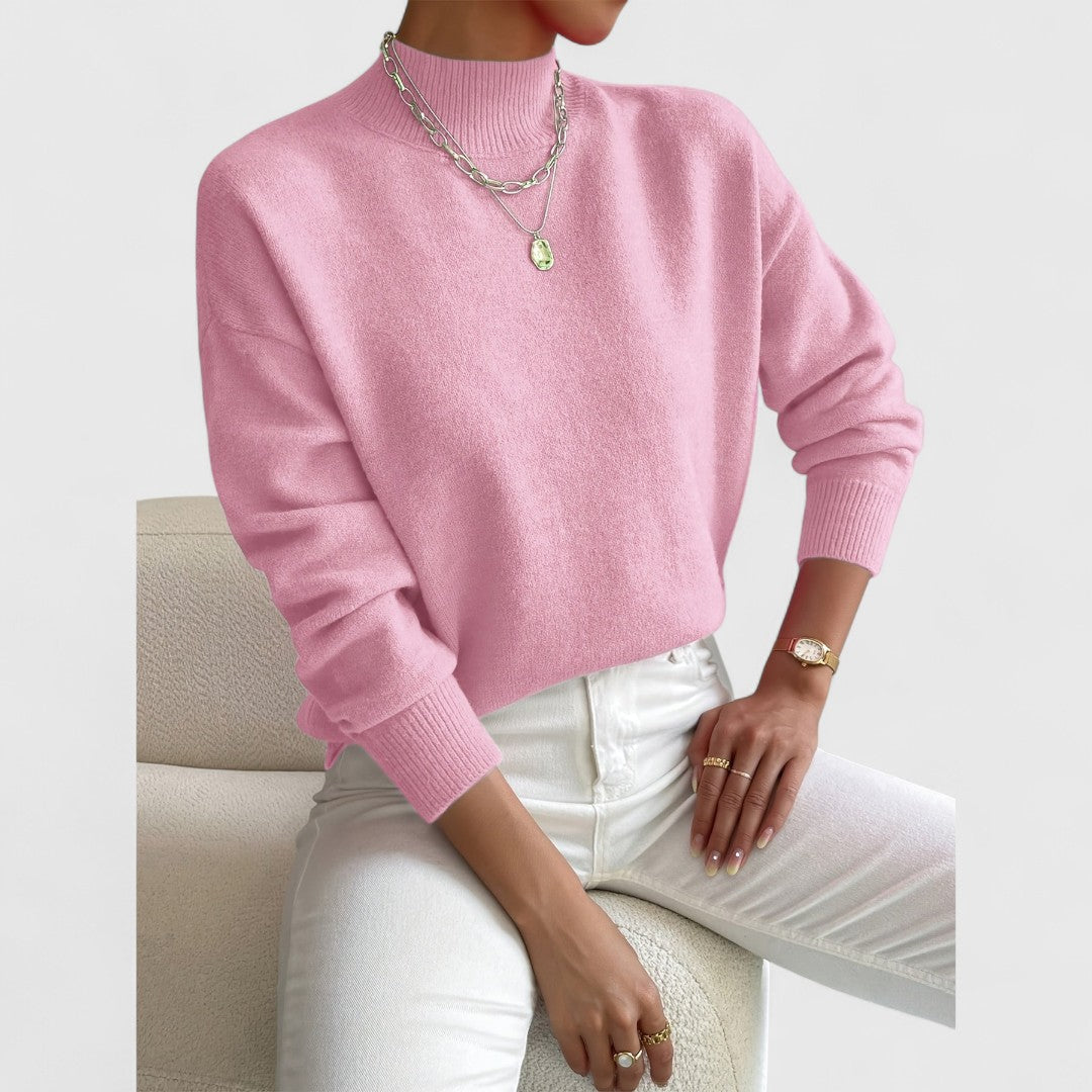 Model draagt de roze trui met ribkraag, lange mouwen en ribboorden, gecombineerd met witte broek en zilveren kettingen. 5
