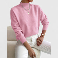 Model draagt de roze trui met ribkraag, lange mouwen en ribboorden, gecombineerd met witte broek en zilveren kettingen. 5