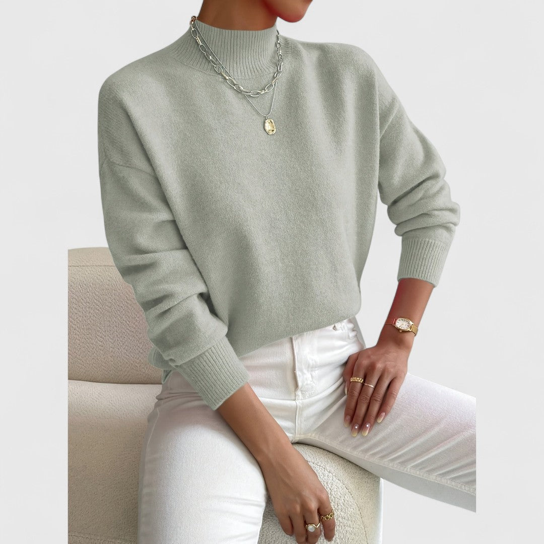 Tweede foto van de saliegroene trui op een model, iets scherper uitgesneden, met ribkraag, ribboorden en witte broek. 3