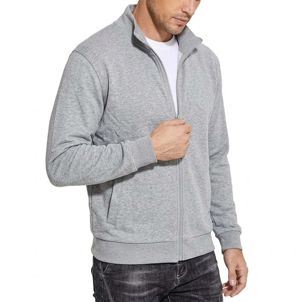 Lichtgrijs gemêleerde sweatshirtjack in halve zijaanzicht, model houdt de rits vast; opstaande kraag en steekzak zichtbaar. 2