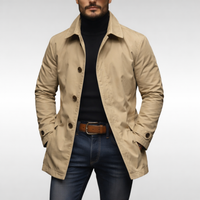 Model draagt de beige jas met bruine knopen over een zwarte coltrui, spijkerbroek en bruine riem. 5