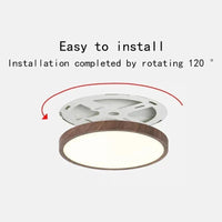 Ronde plafondlamp met donkere houtlook rand en wit montagebeugeltje erboven, met rode pijl die de draaiende montage laat zien. 1