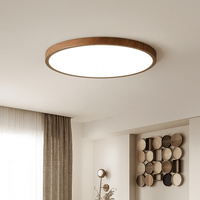 Ronde ultradunne lamp met bruine houtlook rand aan het plafond van een lichte kamer met gordijnen en wanddecoratie. 11