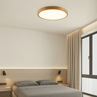 Ronde plafondlamp met warm licht en lichte houtlook rand in een slaapkamer met houten hoofdbord en grijze kussens. 13