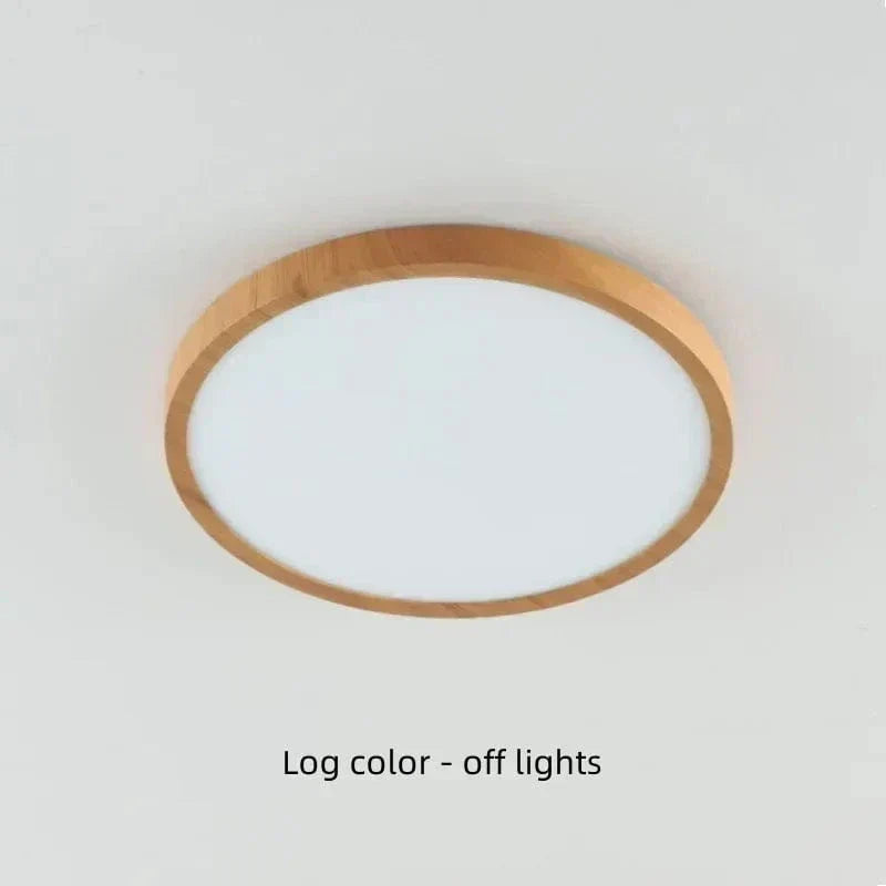 Uitgeschakelde ronde plafondlamp met lichte houtlook rand en melkwitte diffuser tegen een licht plafond. 19