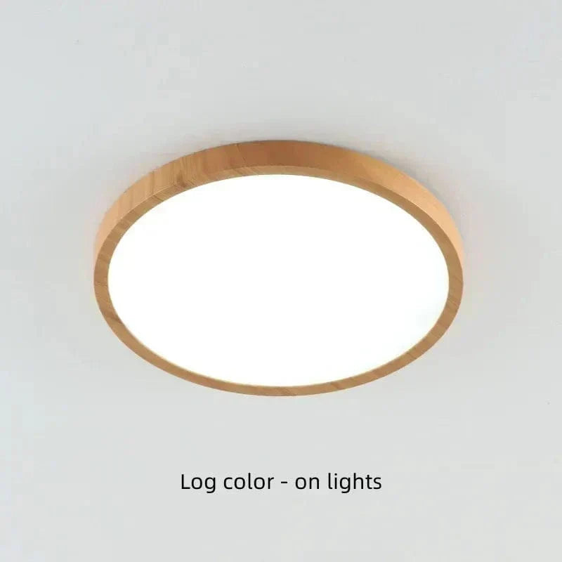 Ingeschakelde ronde plafondlamp met lichte houtlook rand en helder verlichte witte diffuser tegen een licht plafond. 20