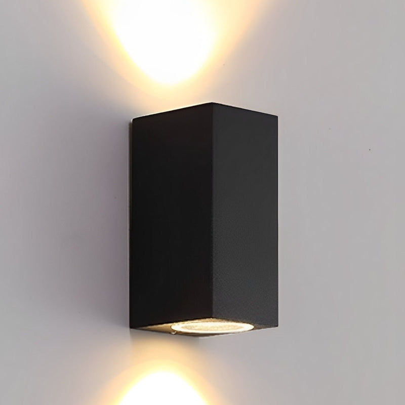 Zwarte langwerpige wandlamp die warm licht tegelijk omhoog en omlaag over een lichte muur werpt 3