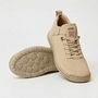 Beige sneaker met veters en elastische band, met een tweede schoen ernaast waarvan de profielzool met ronde noppen zichtbaar is. 1