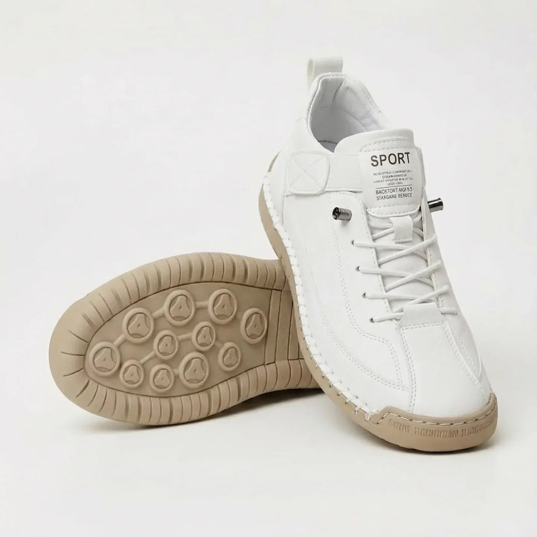 Witte sneaker met elastische veters en beige zool, schuin gezet naast een schoen waarvan de noppenzool naar boven wijst. 2
