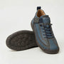 Blauwgrijze sneaker met donkerblauwe veters en bruingrijze zool, schuin gezet naast een schoen met de zoolzijde omhoog. 6