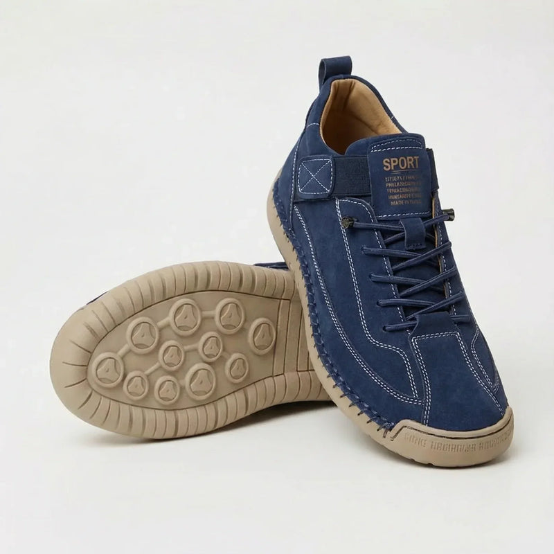 Donkerblauwe suèdelook sneaker met lichte siernaden en beige zool, met de noppenzool van de tweede schoen in beeld. 7