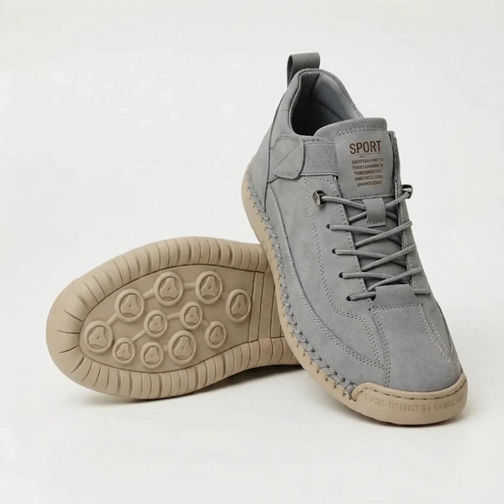Lichtgrijze sneaker met grijze veters en beige zool, naast een schoen waarvan de zool met ronde noppen te zien is. 8