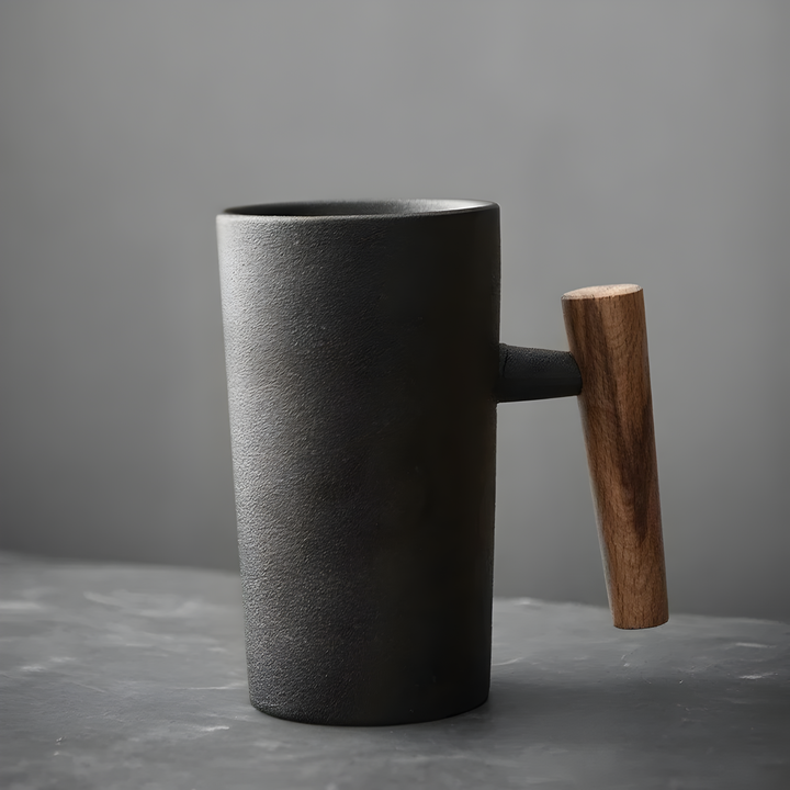 Zwarte mok met ruw mat oppervlak en een houten handvat van donkerder hout, schuin van voren 2