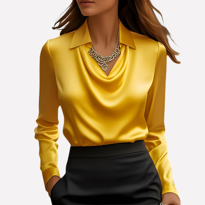 Vrouw draagt de blouse in geel met een zwarte rok en een opvallende statement-ketting 10