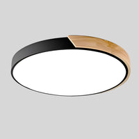 Zwarte ronde plafondlamp met houten accent langs een deel van de rand, los afgebeeld op lichtgrijze achtergrond. 17
