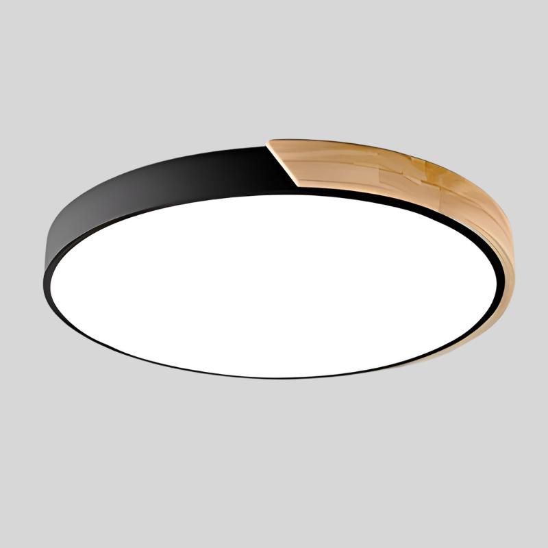 Zwarte ronde plafondlamp met houten accent langs een deel van de rand, los afgebeeld op lichtgrijze achtergrond. 17