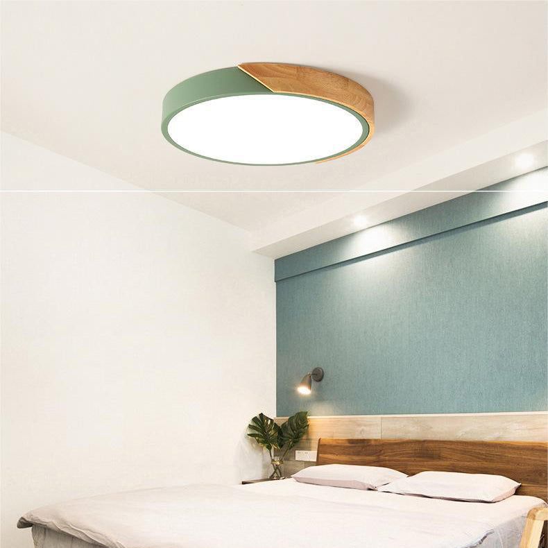 Groene ronde plafondlamp met houten accent aan de rand, brandend boven een slaapkamer met houten hoofdbord. 6