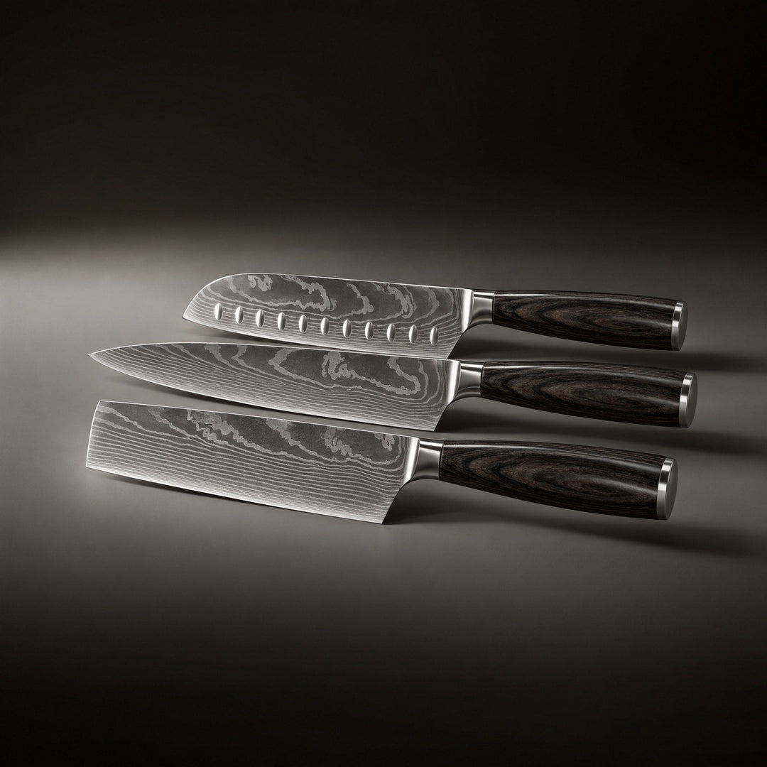 De drie messen naast elkaar liggend van boven naar beneden, met een santoku met kuiltjes, een koksmes en een hakmes. 2