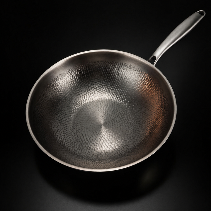 Wokpan van bovenaf gezien, met het gehamerde schubbenpatroon in de binnenkant goed zichtbaar en de steel rechtsboven. 2