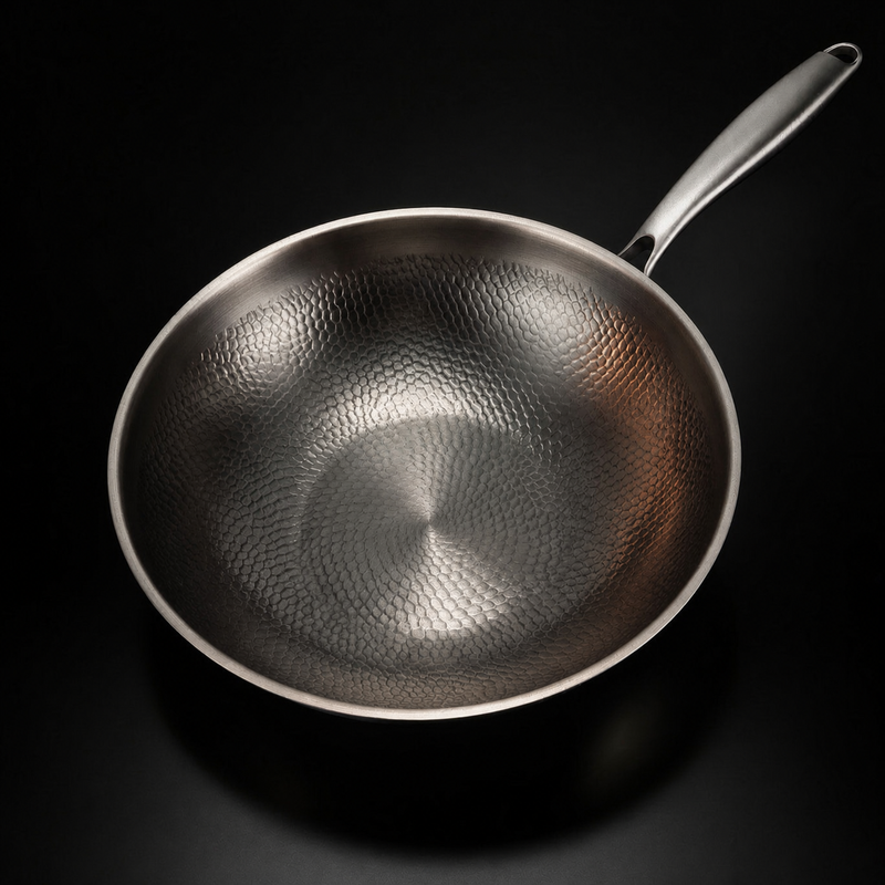 Wokpan van bovenaf gezien, met het gehamerde schubbenpatroon in de binnenkant goed zichtbaar en de steel rechtsboven. 2
