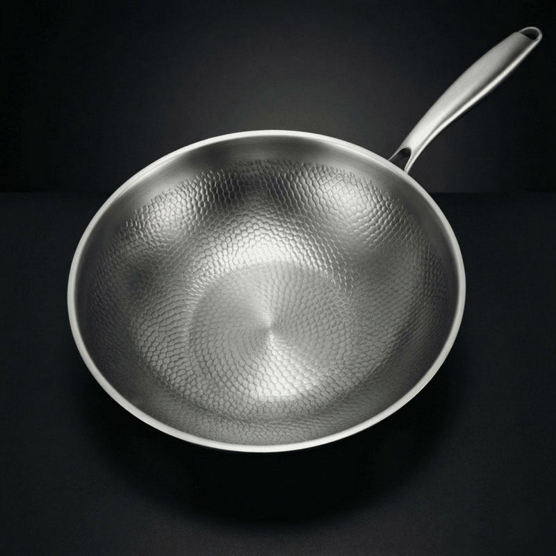 Bovenaanzicht van de lege wokpan met het gehamerde patroon aan de binnenkant en de steel naar rechtsboven. 2