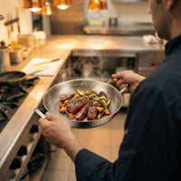 Kok houdt de pan aan beide handgrepen vast in een keuken, gevuld met gebakken biefstukreepjes en groenten. 6