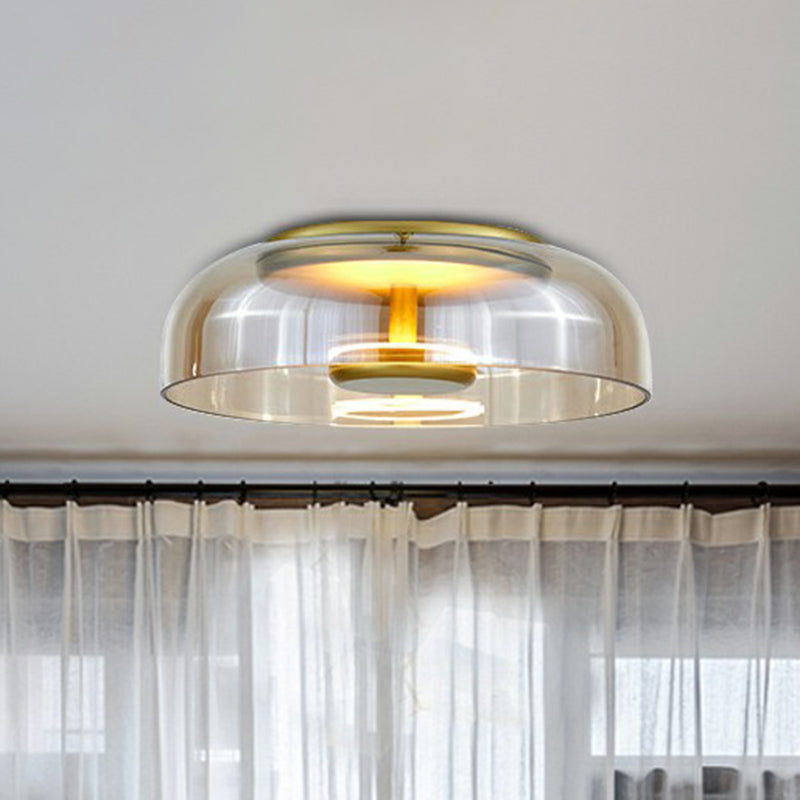 Plafondlamp met amberkleurig glas en gouden afwerking, brandend boven een raam met witte vitrage 2