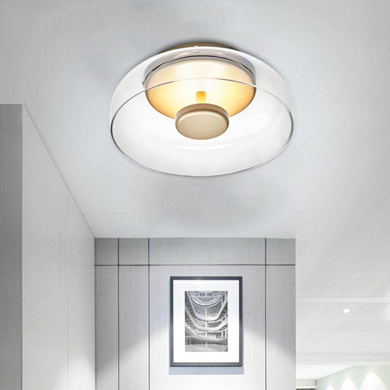Plafondlamp met helder glas en gouden middenstuk, brandend in een lichte gang met ingelijste foto 3