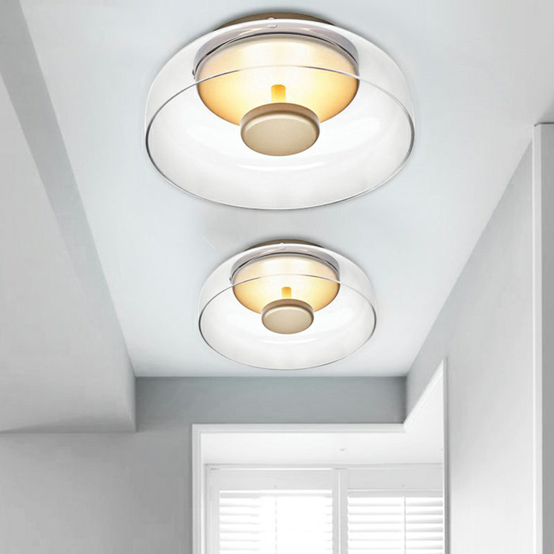Twee heldere glazen plafondlampen in twee maten, naast elkaar aan het plafond van een lichte gang 4
