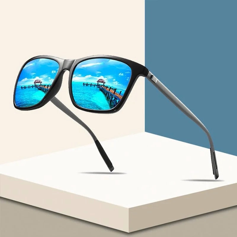 Zwarte zonnebril met blauw spiegelende glazen waarin een steiger aan zee weerkaatst, op een wit podium 1