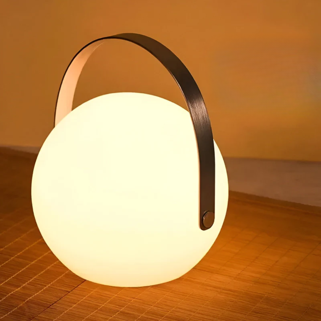 Ronde bollamp met brede zwarte handgreep gloeit warm op een rieten ondergrond 15