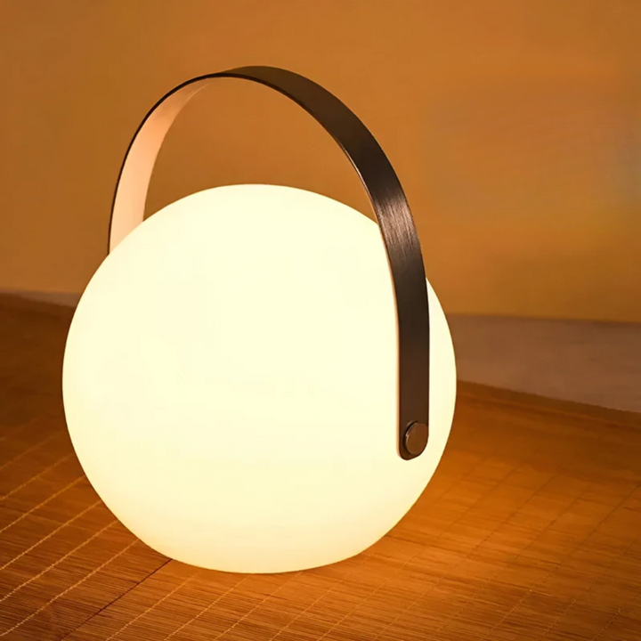 Ronde bollamp met brede zwarte handgreep gloeit warm op een rieten ondergrond 15