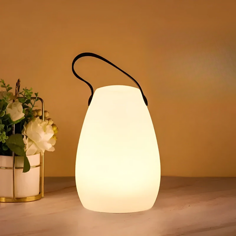 Druppelvormige lamp met zwarte lus brandt warm naast een bloemstuk op een lichte tafel 14