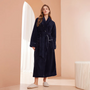 Model in marineblauwe badjas met sjaalkraag en ceintuur, in een roze kamer met boog 1