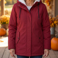 Close-up van de rode parka aan het lijf, met trekkoord, klepzakken en herfstdecor met pompoenen 2