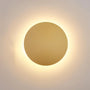 Close-up van de goudkleurige ronde wandlamp met een warme gloed rondom de schijf 1
