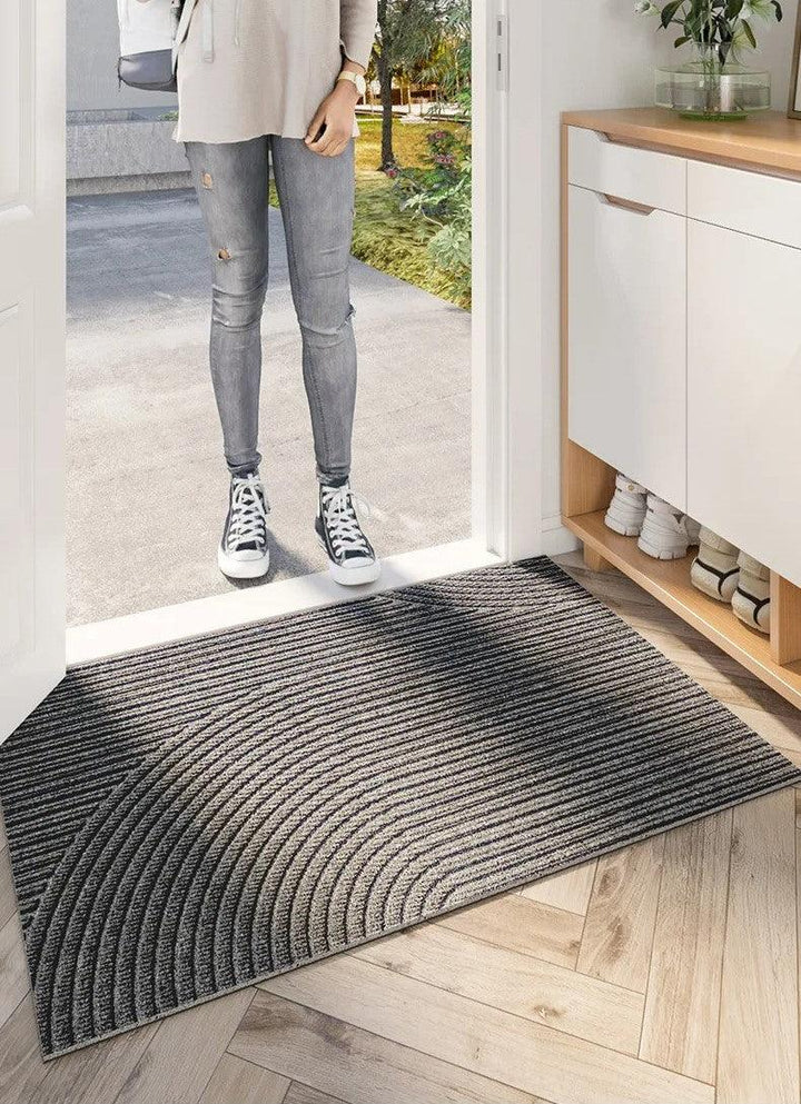 Vrouw in spijkerbroek en sneakers staat voor de ingang met een grijze gestreepte deurmat 8