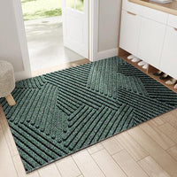 Groene deurmat met reliëfpatroon van diagonale en driehoekige ribbels, gelegd in een lichte hal bij de openstaande voordeur. 1