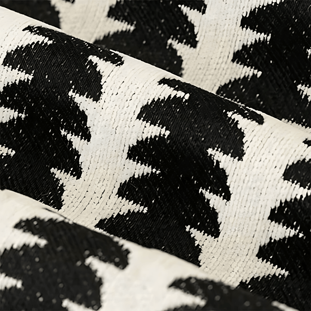 Close-up van de geweven chenille stof in zwart en crème, met het patroon en de dichte textuur van de draden zichtbaar. 2