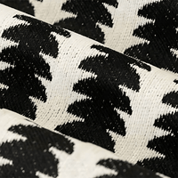 Close-up van de geweven chenille stof in zwart en crème, met het patroon en de dichte textuur van de draden zichtbaar. 2